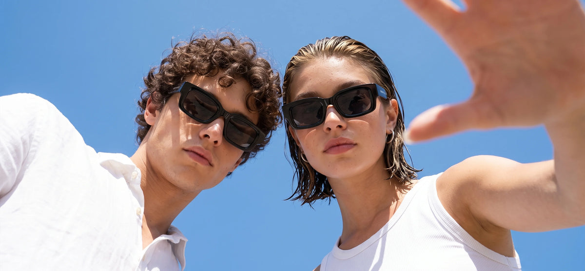 Man and woman wearing black Waylon Smith sunglasses against a blue sky, mobile home page bannerslider_item_XGXPpK